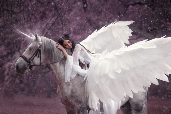 جلف زیبا جوان با راه رفتن با یک اسب شاخدار او نور نور باور نکردنی لباس سفید پوشانده است دختر بر روی اسب است زیبای خفته عکاسی هنری