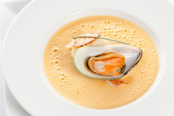سوپ هویج با غذاهای دریایی در پس زمینه سفید