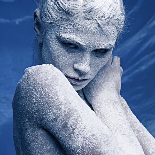 پرتره از یک دختر زیبا در یخبندان در چهره اش در زمینه یخ آبی