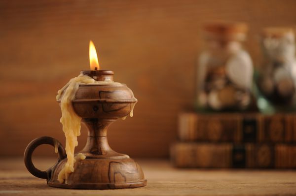 شمع قدیمی بر روی میز چوبی کتاب های قدیمی در پس زمینه