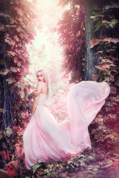 زن جوان رمانتیک زیبایی در لباس نوعی پارچه ابریشمی بلند با قرار دادن لباس در جنگل فانتزی در غروب آفتاب دختر خوش تیپ عروس و لذت بخش از طبیعت در فضای باز لباس شلوغ