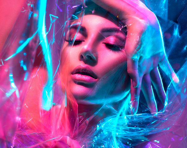دختر مدل مد بالا در چراغ های نئون روشن و رنگارنگ که از طریق فیلم شفاف در استودیو قرار می گیرد پرتره زن زیبا در UV طراحی هنری رنگارنگ را تشکیل می دهند در پس زمینه رنگارنگ و واضح