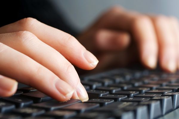 دستان زن در صفحه کلید کامپیوتر تایپ می کنند