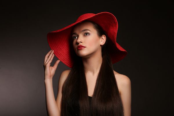 یک زن با یک کلاه قرمز روی یک پس زمینه سیاه به دنبال
