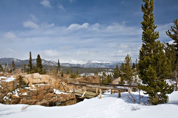 پل پای چوبی در زمستان قله های برفی در فاصله پارک ملی Rocky Mountain کلرادو ایالات متحده آمریکا