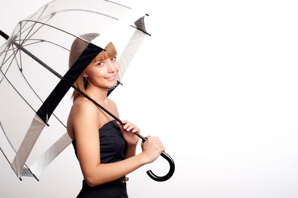 زن جوان مد روز لبخند می زند و چتر را در دست می گیرد