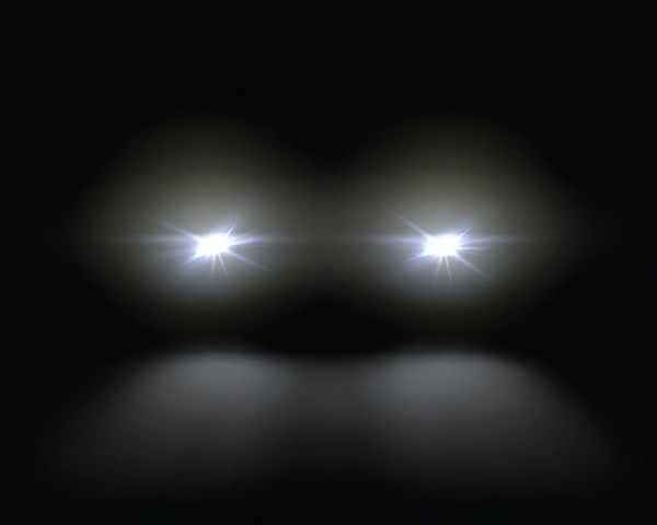 تصویر برداری چراغهای جلو اتومبیل سفید که از زمینه تاریکی الگوی چراغ می درخشد جدا شده بر روی زمینه سیاه