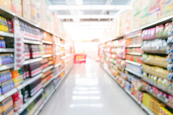 یک راهرو سوپر مارکت با قفسه های رنگارنگ تاری