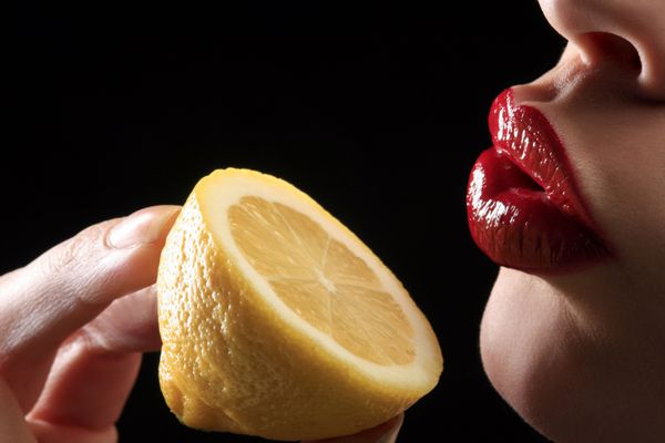 لبهای زن قرمز با لیمو نگه داشتن دست