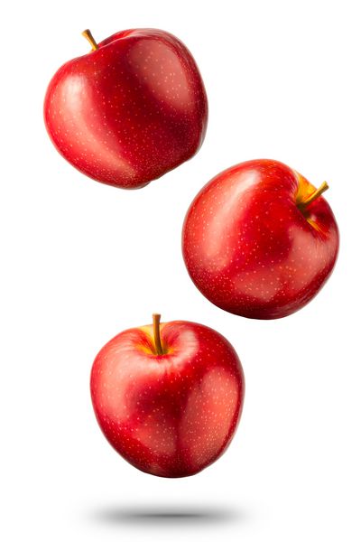 سیب های قرمز در حال سقوط جدا شده در پس زمینه سفید با مسیر قطع و بازتاب های براق