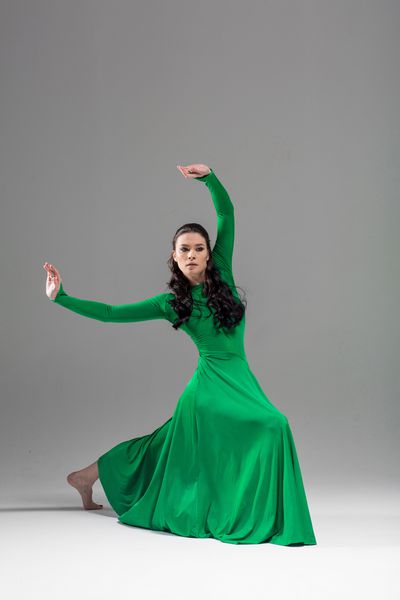رقاصه زیبا جوان در لباس سبز زیبا شلیک فضای کپی پس زمینه خاکستری