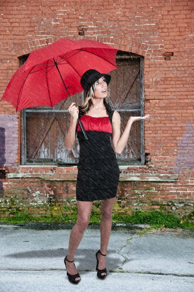 یک زن جوان زیبا که چتر در باران دارد