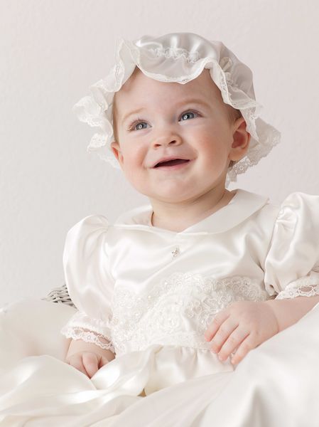 دختر بچه کودک کوچک که روی صندلی در داخل خانه نشسته و به زیبایی لباس لبخند می زند