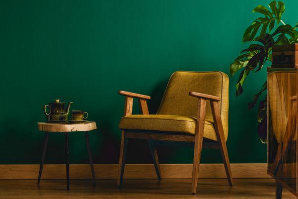 صندلی زرد در فضای داخلی اتاق پرنعمت با دیوارهای سبز مدفوع کابینت قوری و گیاه