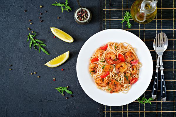 اسپاگتی ماکارونی با میگو گوجه فرنگی و جعفری وعده غذایی سالم غذای ایتالیایی نمای بالا دراز کشیدن