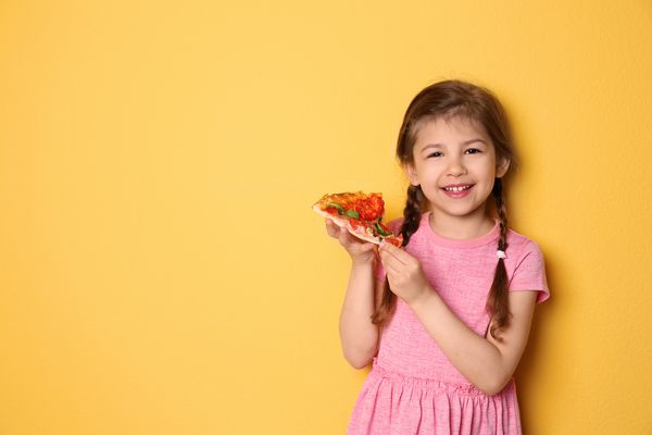 دختر بچه ناز با برش پیتزا در زمینه رنگی