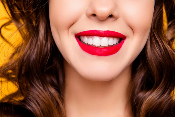 نزدیک چهره نیمی از چهره زن دندانپزشک را با لبخند پرتوی لبهای قرمز قرمز و سفید و سالم سالم جدا شده در مفهوم تبلیغات پس زمینه زرد ببندید