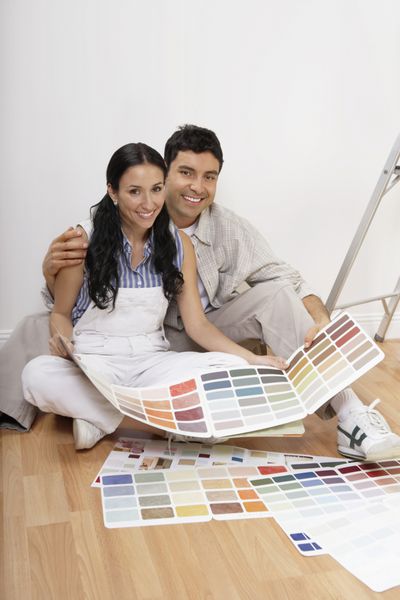 یک زوج خوشبخت با نمونه های رنگی برای رنگ آمیزی آپارتمان جدید خود