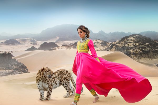 عکس هنری زیبا از یک دختر با لباس صورتی بلند که از طریق بیابان با یک پلنگ قدم می زند