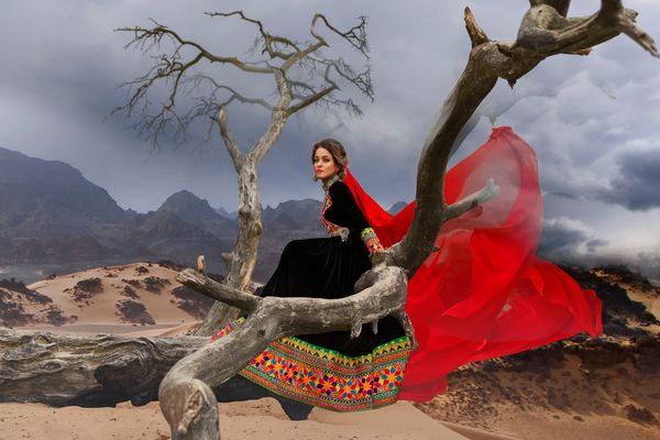 عکس رویایی از دختری با لباس سیاه و سفید سنتی آرکان anarkali و روسری قرمز او که روی یک درخت نشسته است