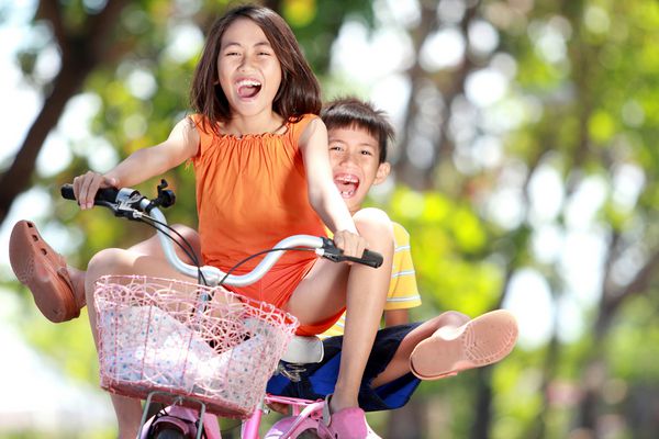 بچه های خندان از دوچرخه سواری در فضای باز لذت می برند