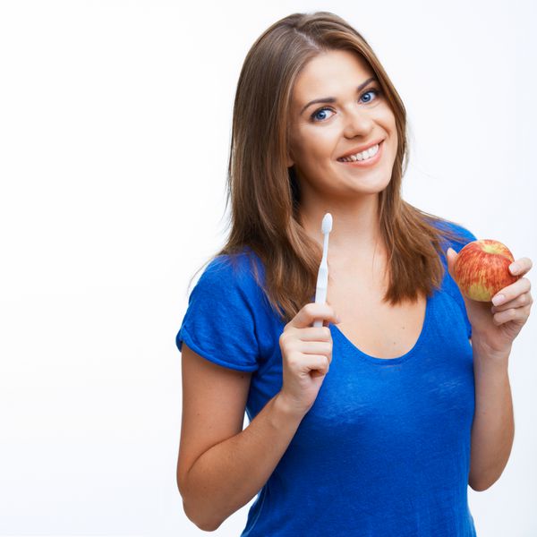 زن با قلم موی دندان و سیب قرمز جدا شده روی سفید