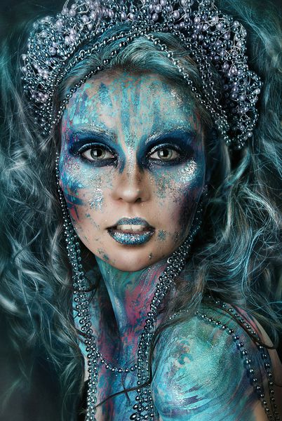 نزدیک عکس پرتره دختر زیبا با نقاشی چهره روشن و آبی روشن آرایش حرفه ای هالووین دختر آبی شگفت انگیز با مدل موی سرسبز