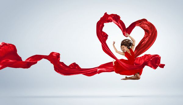زن جوان در استودیو و نماد قلب با پارچه قرمز می رقصید
