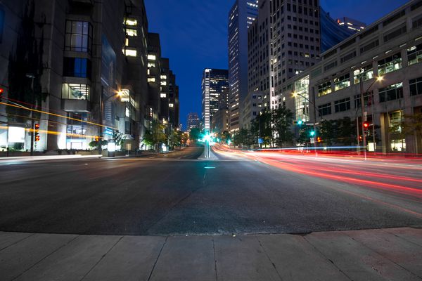 خیابان دانشگاه در مونترال با اتومبیل های سیلته با چراغ عقب قرمز و چراغ راهنمایی در اوایل صبح با ساختمان اداری در پس زمینه تا غروب