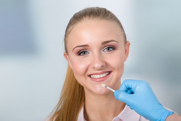 استفاده از راهنمای سایه در دهان زن زیبا برای بررسی روکش دندان