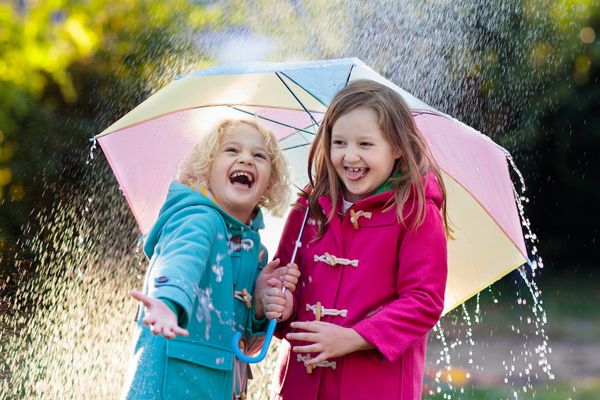 بچه ها با چتر رنگارنگ در باران دوش پاییز دختر و پسر كوچك در كف دوقلوی گرم در یك بوستان با هوای بارانی بازی می كنند سرگرمی در فضای باز برای کودکان بچه ابتلا به قطرات باران