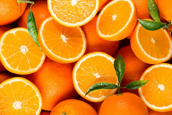 نمای بالای میوه های تازه برداشت شده درخت نارنج با برگ های سبز پرتقالهای آلی