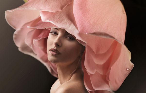 زن جوان زیبا که گل رز را به عنوان کلاه پوشیده است