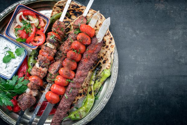 کباب آردانا سنتی و کباب ششلیک شرقی با گوجه فرنگی و پهن بریده به عنوان نمای بالا روی صفحه با فضای کپی درست