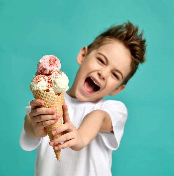 کودک پسر بچه بستنی وانیلی توت فرنگی را در مخروط وافل نگه دارید و لبخند بر لب بلند فریاد زاری بر روی زمینه نعناع آبی با فضای کپی متن آزاد