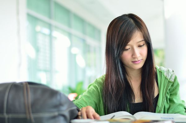 دانشجوی جوان زیبا آسیایی در حال خواندن بود