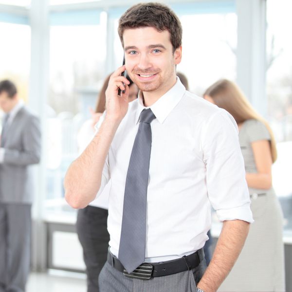 یک مرد جوان خوش تیپ تجاری با تلفن در ساختمان اداری