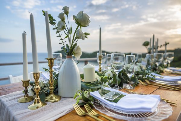 جدول چیدانه جدول عروسی رمانتیک بدون قرار دادن مکان گرمسیری مردم با کارد و چنگال های طلایی و منظره منظره از غروب خورشید با فضای کپی