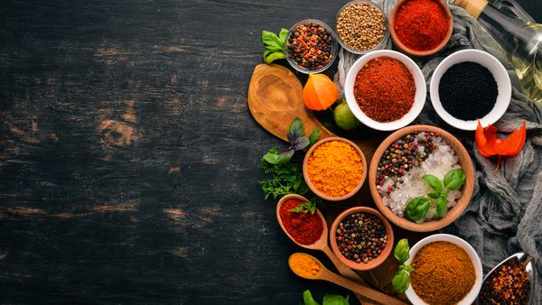 مجموعه ای از ادویه ها و گیاهان غذاهای هندی فلفل نمک پاپریکا ریحان زردچوبه روی تخته سیاه چوبی نمای بالا فضای کپی رایگان