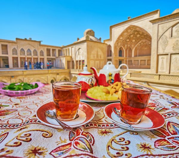 رستوران سنتی ایرانی چای خوشمزه با شیرینی های محلی روی سینی آب نبات های شکر و بادام بادام کاشان ایران را ارائه می دهد