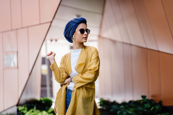 پرتره مد زن جوان و جذاب مسلمان مالایی در این شهر او با یک عمامه دریایی روسری روسری حجاب و عینک آفتابی خوش لباس و شیک است او در حال نمایش برای عکس خود است