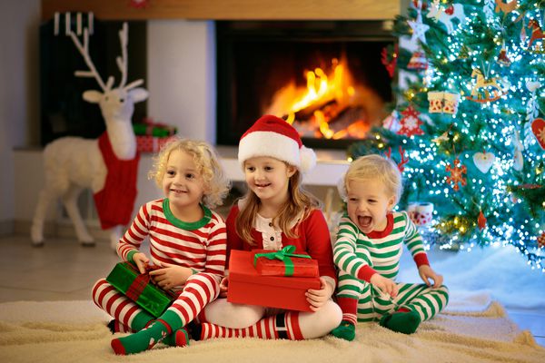 کودکان در شب کریسمس و شومینه در آستانه Xmas خانواده با بچه ها کریسمس را در خانه جشن می گیرند دختر و پسر در تطبیق لباس خوابها در تزئین درخت کریسمس و افتتاحیه هدایا هدایای تعطیلات برای بچه ها