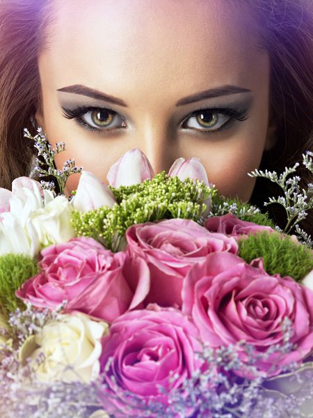 صورت نزدیک دختر زیبا با گل زن جذاب جوان دسته گلهای بهاری را نگه می دارد