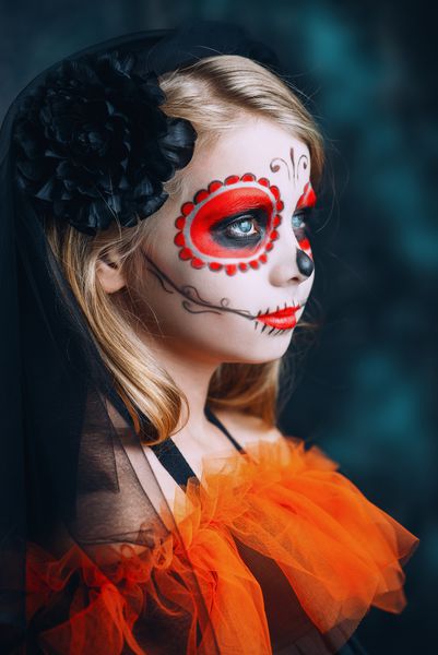 پرتره دختر بچه ای با لباس Calavera Catrina در پس زمینه grunge تیره دخترک با آرایش جمجمه قند مهمانی هالووین Dia de los muertos روز مرگ