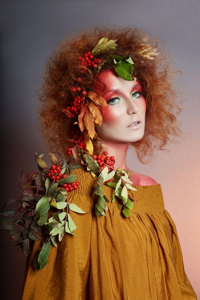 پرتره هنری خانم ها در پاییز در موهای او رنگ های روشن پاییز و آرایش موهای مجعد قرمز و موهای حجیم برگ و انواع توت درخت روون بر روی سر و شانه های دختر