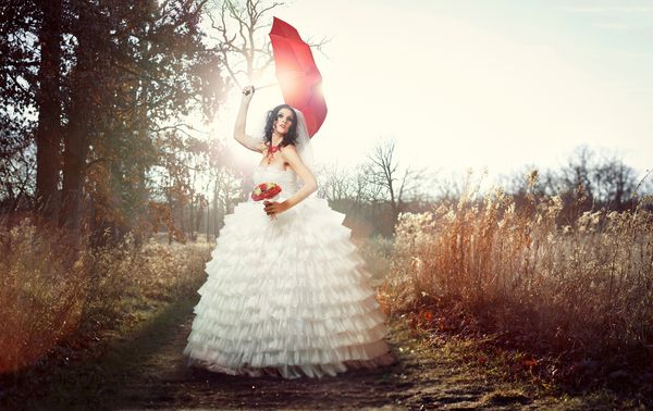 عروس زیبا و جوان در لباس سفید که دارای گل رز قرمز است