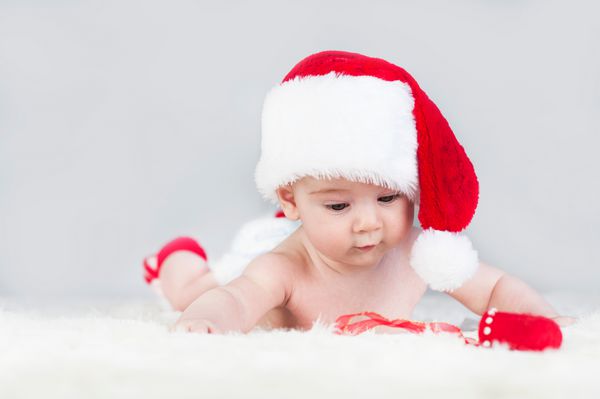 کودک بسیار زیبا و عاطفی روشن بسیار زیبا و شاد در کلاه سانتا که بر روی تخته سفید میخورد