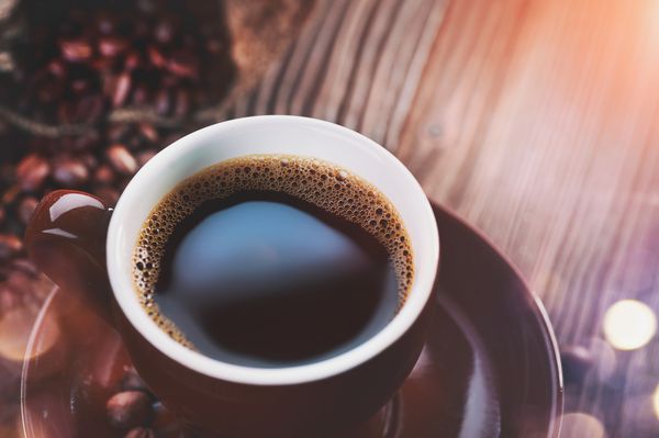 قهوه فنجان قهوه و لوبیا بو داده را در نزدیکی میز چوبی قرار دهید اسپرسو تمرکز نرم