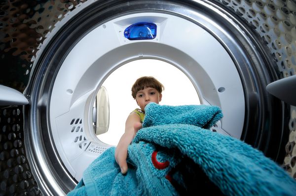 پسران خنده دار بارگیری لباس به ماشین لباسشویی نمای از داخل ماشین لباسشویی
