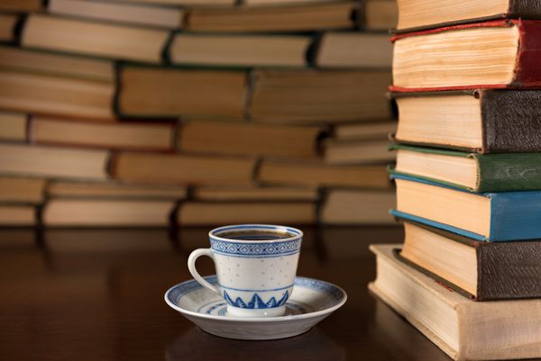 کتاب و یک فنجان قهوه روی یک میز چوبی
